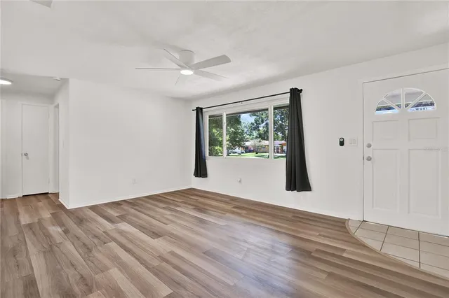 a view of empty room with wooden floor and fan