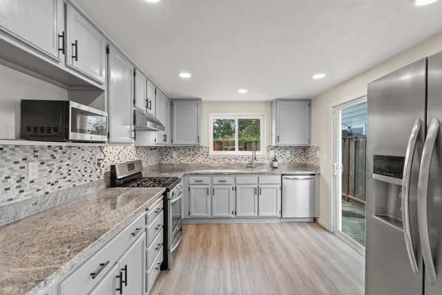 a kitchen with stainless steel appliances granite countertop a sink stove and refrigerator