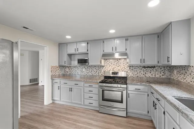 a kitchen with granite countertop white cabinets and stainless steel appliances