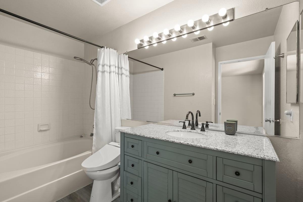 52 Winding Way Watsonville, CA 95076 - Photo 19 of 29 a bathroom with a granite countertop sink a toilet a mirror a bathtub and shower