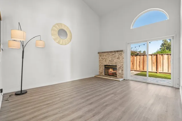 an empty room with windows fireplace and wooden floor