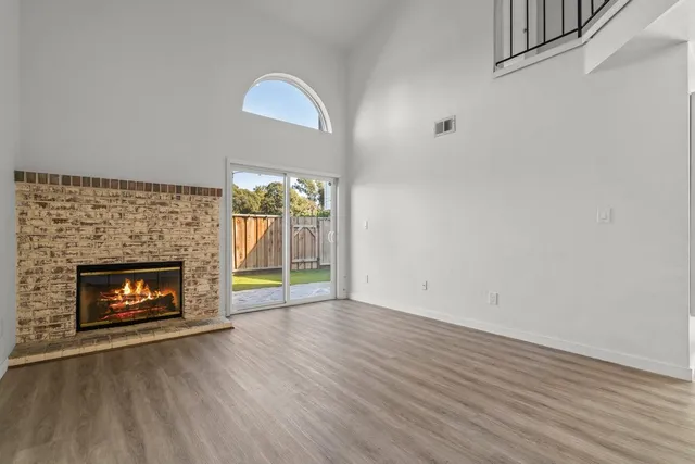 a view of an empty room with wooden floor fireplace and a window
