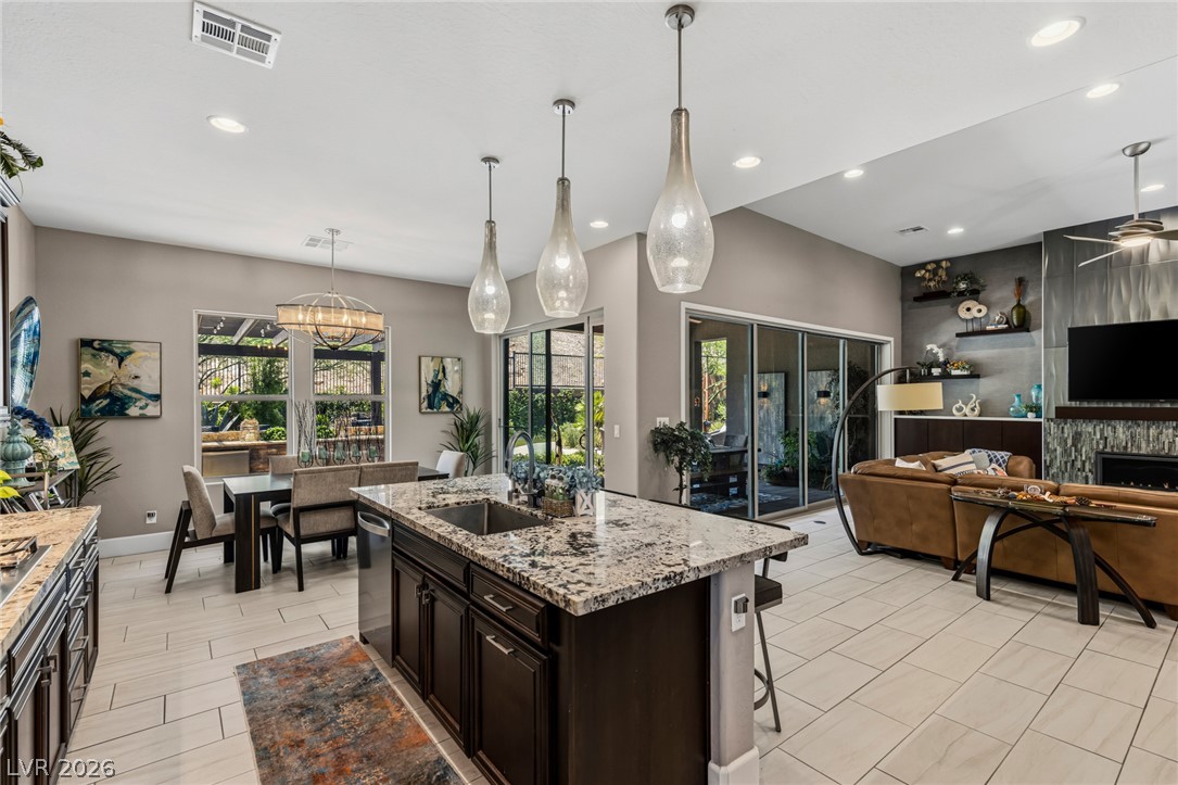 10167 Copper Edge Road Las Vegas, NV 89148 - Photo 11 of 45 A contemporary open-concept layout connects a well-appointed kitchen to a inviting living space, all overlooking a lush outdoor setting.