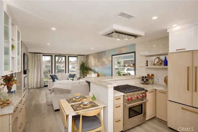 a kitchen with stainless steel appliances granite countertop a refrigerator a stove and a dining table with wooden floor