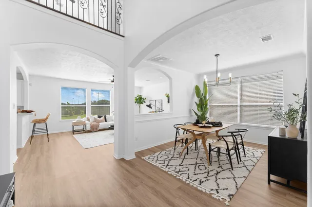 a living room with furniture large window and wooden floor