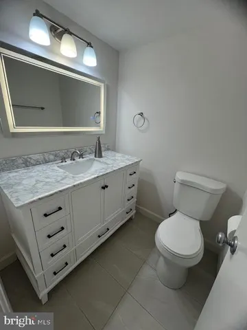 a bathroom with a granite countertop toilet sink and mirror