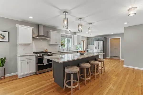 a large kitchen with stainless steel appliances granite countertop a large stove a sink dishwasher and a refrigerator with wooden floor