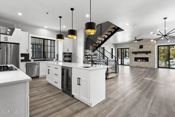 a kitchen with stainless steel appliances kitchen island granite countertop a stove a refrigerator a sink dishwasher and a dining table with wooden floor