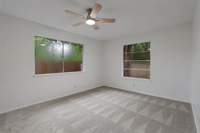 an empty room with windows and fan