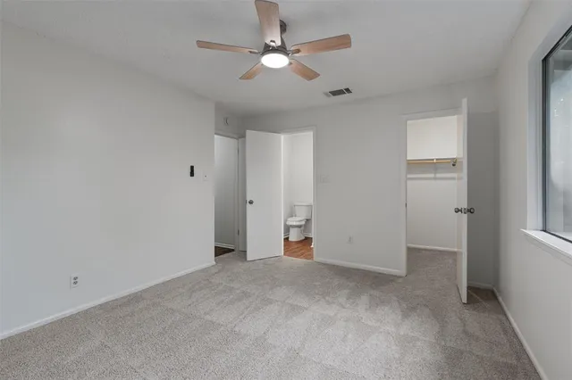 an empty room with closet and a ceiling fan