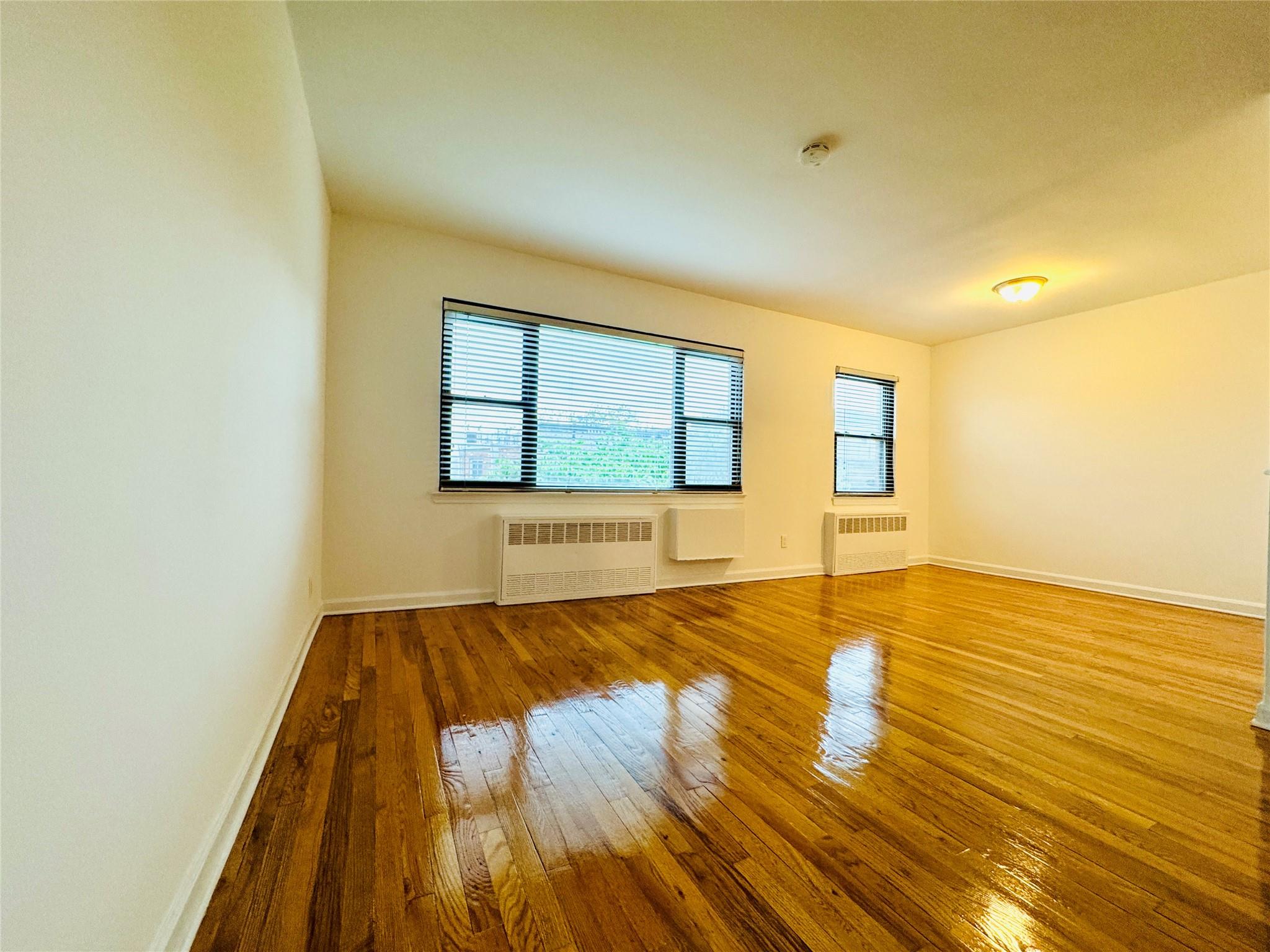 41-07 56th Street, Unit 3 Queens, NY 11377 - Photo 2 of 13 a view of an empty room with wooden floor and a window