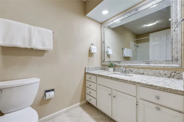 a bathroom with a granite countertop toilet sink and mirror