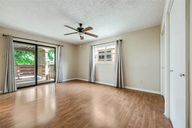 a view of an empty room with a window and wooden floor