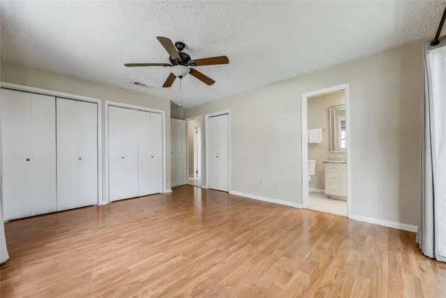 a view of empty room with wooden floor and ceiling fan