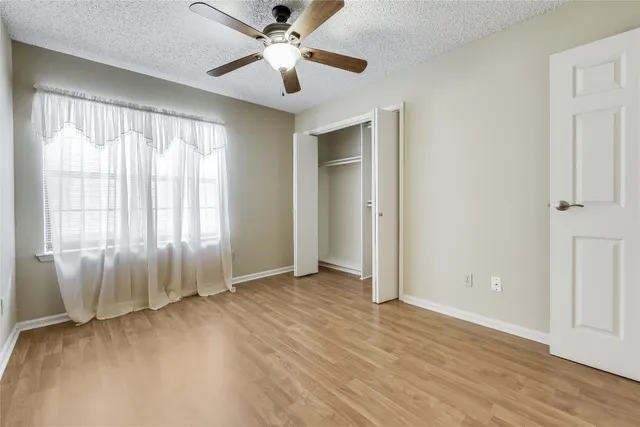 an empty room with wooden floor and windows with curtains