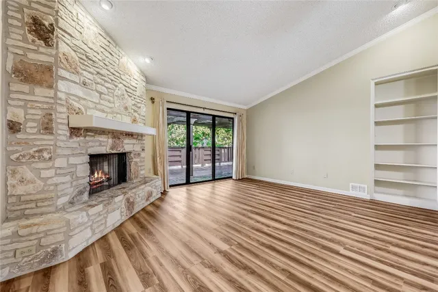 a view of an empty room with wooden floor fireplace and a window