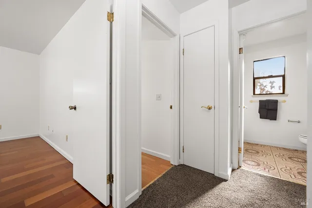 a view of hallway with window and wooden floor