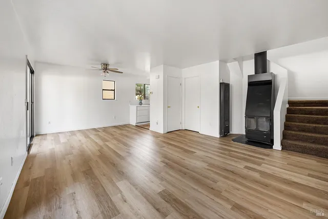an empty room with wooden floor and entrance to ceiling window