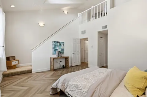 a bedroom with a bed and dresser with wooden floor