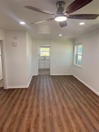 a view of empty room with wooden floor and fan