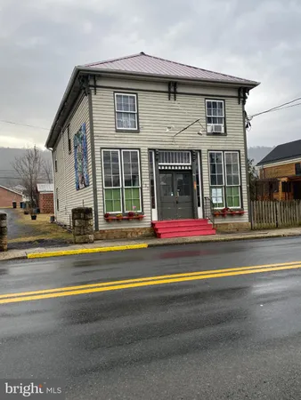 a view of a house with a small yard and large trees