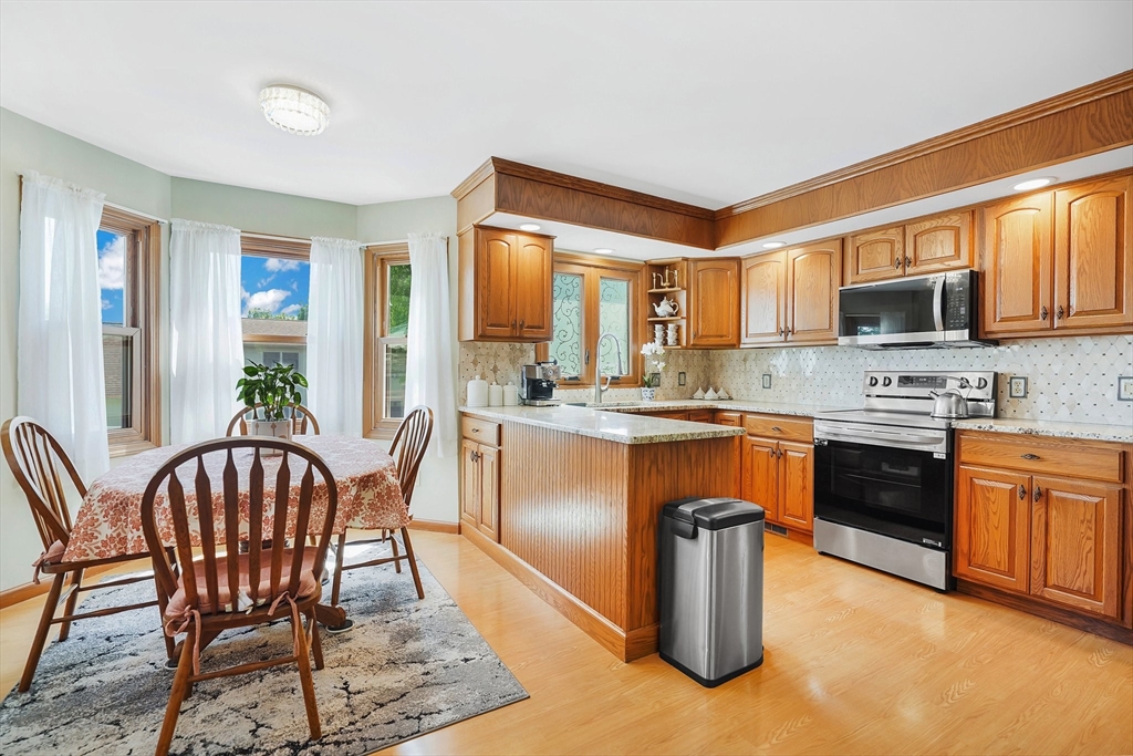 5 Flower Street Springfield, MA 01118 - Photo 17 of 42 a kitchen with stainless steel appliances granite countertop a stove a sink dishwasher a dining table and chairs with wooden floor