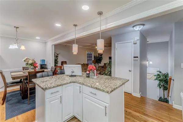 a very nice looking kitchen with granite countertop a stove a sink a dining table and chairs with wooden floor