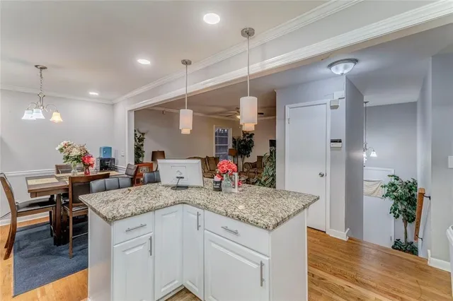 a very nice looking kitchen with granite countertop a stove a sink a dining table and chairs with wooden floor