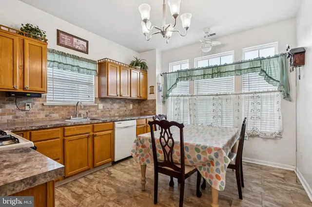 a dining area with stainless steel appliances kitchen island granite countertop a table chairs and a wooden cabinets