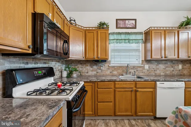 a kitchen with stainless steel appliances granite countertop a sink stove and cabinets