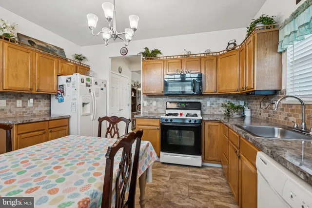 a kitchen with stainless steel appliances granite countertop a sink a stove a refrigerator cabinets and dining table