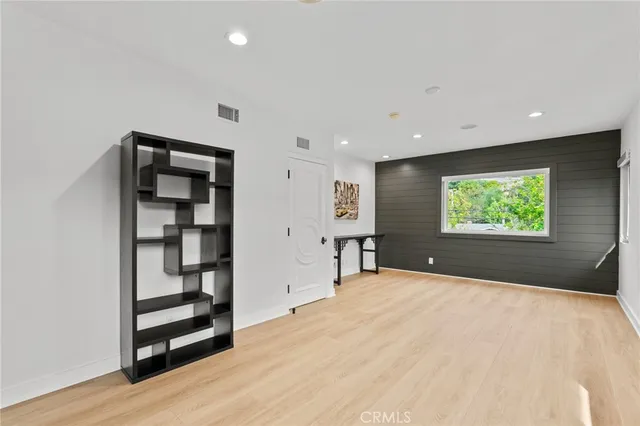 a view of an empty room with window and wooden floor