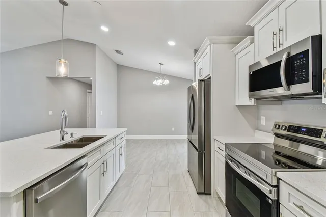 a kitchen that has a sink a microwave oven a stove and white cabinets with wooden floor