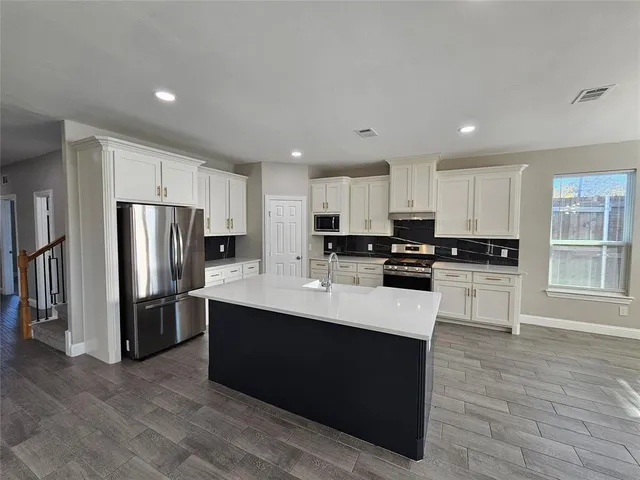 a kitchen with kitchen island a refrigerator sink and cabinets