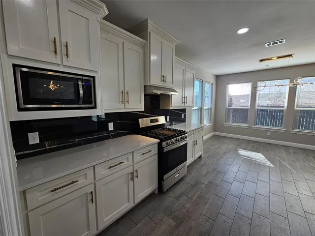 a kitchen with stainless steel appliances granite countertop a stove a microwave and a sink