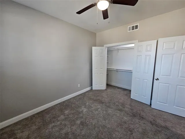 an empty room with closet and a ceiling fan