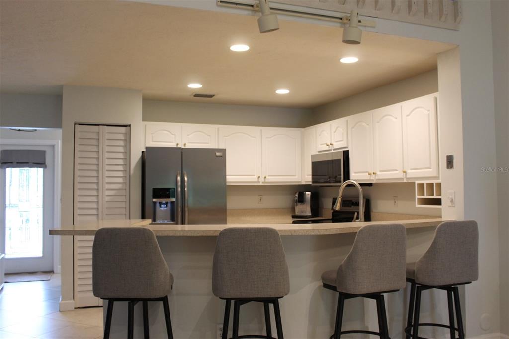 22383 Thousand Pines Lane Boca Raton, FL 33428 - Photo 2 of 28 a kitchen with stainless steel appliances granite countertop a dining table chairs refrigerator and sink