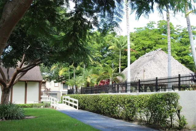 a sign of golf club on a wall under a large tree