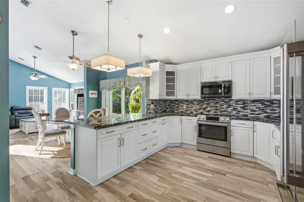a kitchen with stainless steel appliances kitchen island granite countertop a stove a sink and a wooden floors