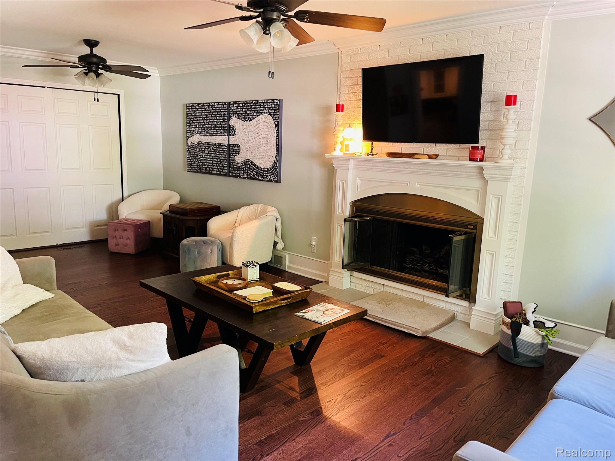 488 Welch Road Northville, MI 48167 - Photo 3 of 22 Living area featuring hardwood flooring, a white brick fireplace with a decorative mantel, and built-in glass fireplace doors