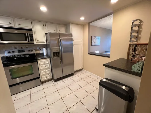 a kitchen with granite countertop a stove sink and refrigerator