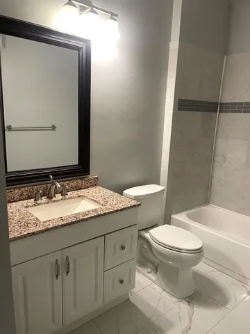 a bathroom with a granite countertop sink toilet and mirror