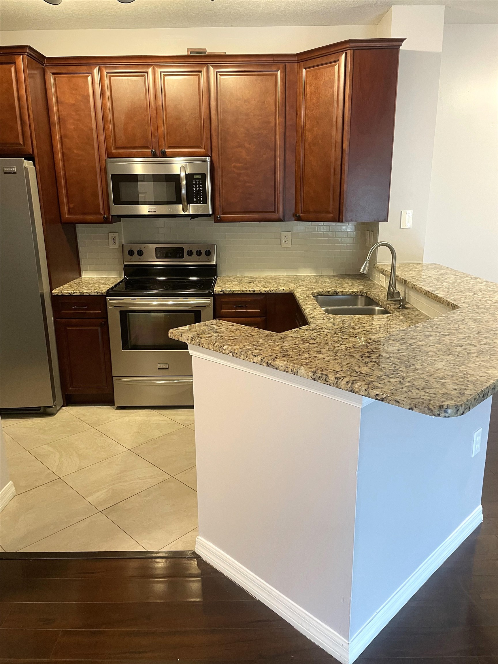 605 Fairway Drive, Unit 107 St. Augustine, FL 32084 - Photo 3 of 20 a kitchen with granite countertop wooden cabinets a stove and a microwave
