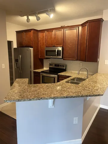 a kitchen with granite countertop wooden cabinets a refrigerator and a sink