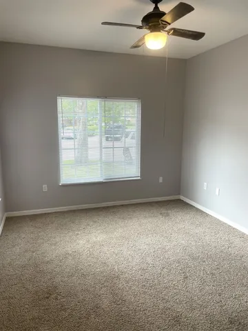 an empty room with a window and a fan