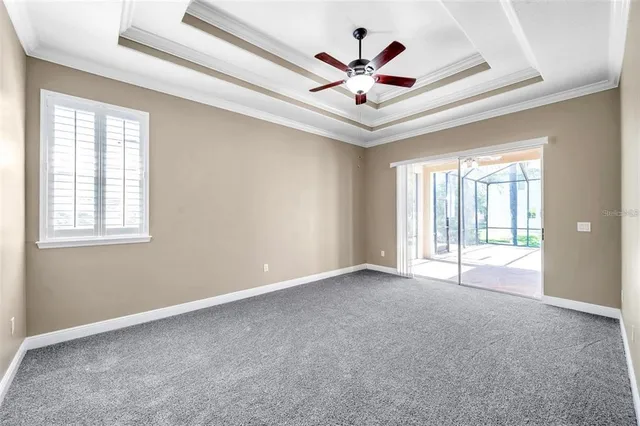 a view of an empty room with chandelier fan and a large window