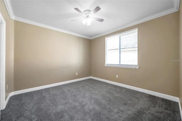 an empty room with windows and ceiling fan