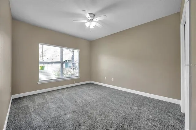 an empty room with windows and chandelier fan