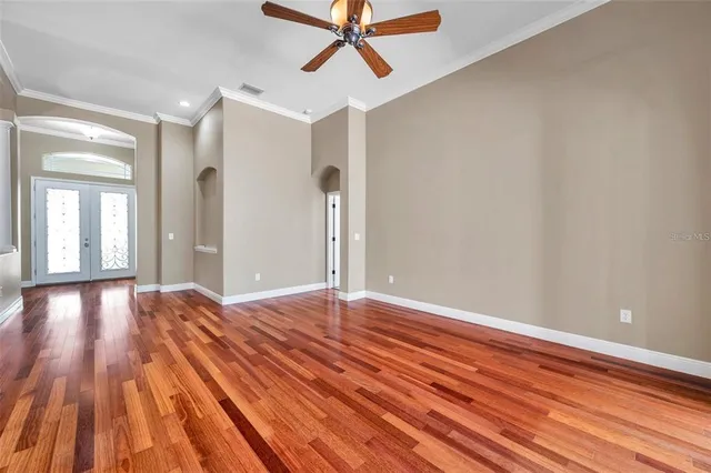 a view of empty room with wooden floor and fan