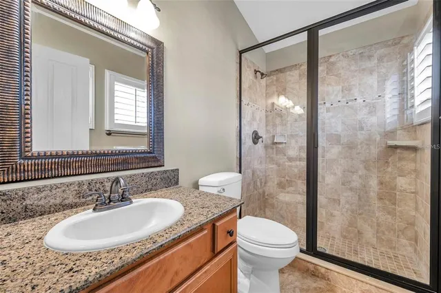 a bathroom with a granite countertop sink toilet and shower